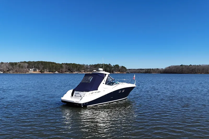 Slide: The Image of 2007 Sea Ray Sundancer 310 boat on a serene lake under clear blue skies. - 3