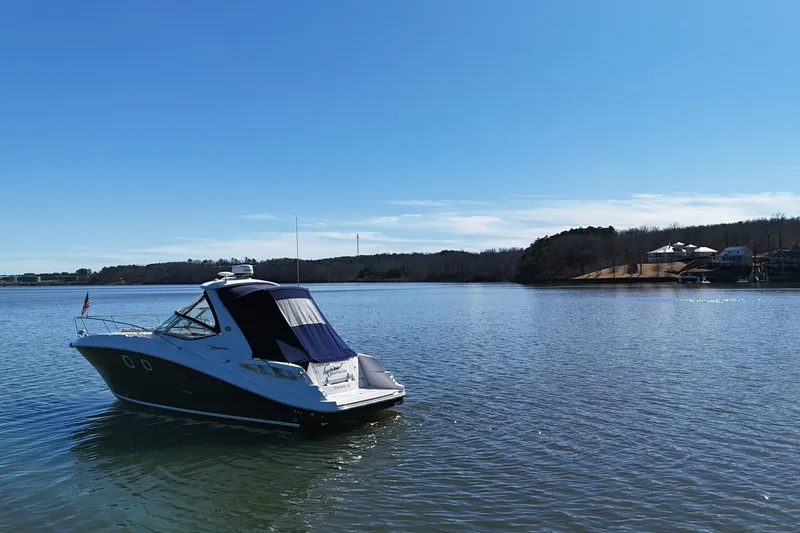 Slide: The Image of 2007 Sea Ray Sundancer 310 yacht on a serene lake under clear blue skies. - 5