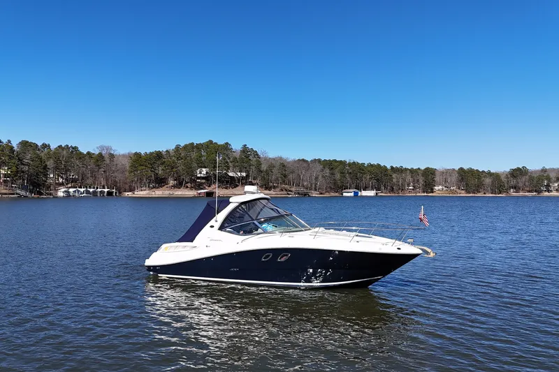 Slide: The Image of 2007 Sea Ray Sundancer 310 yacht on a serene lake under clear blue skies. - 1