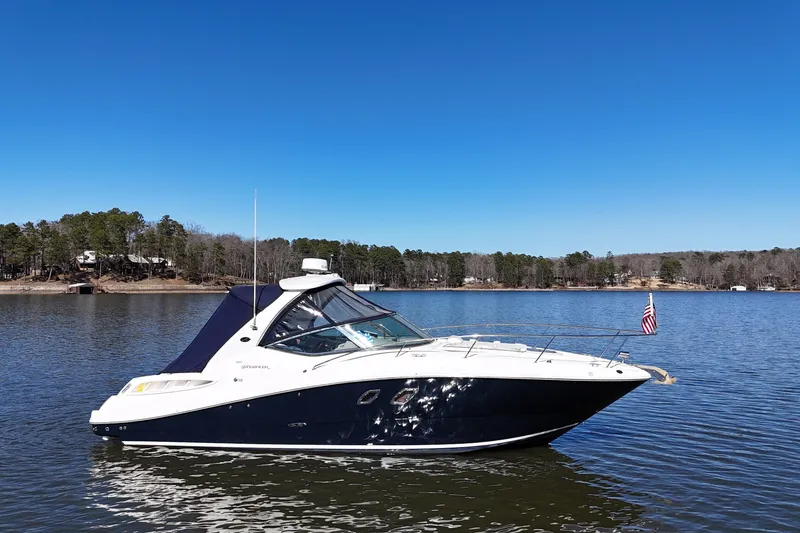 Slide: The Image of 2007 Sea Ray Sundancer 310 yacht on a serene lake with clear blue sky. - 11