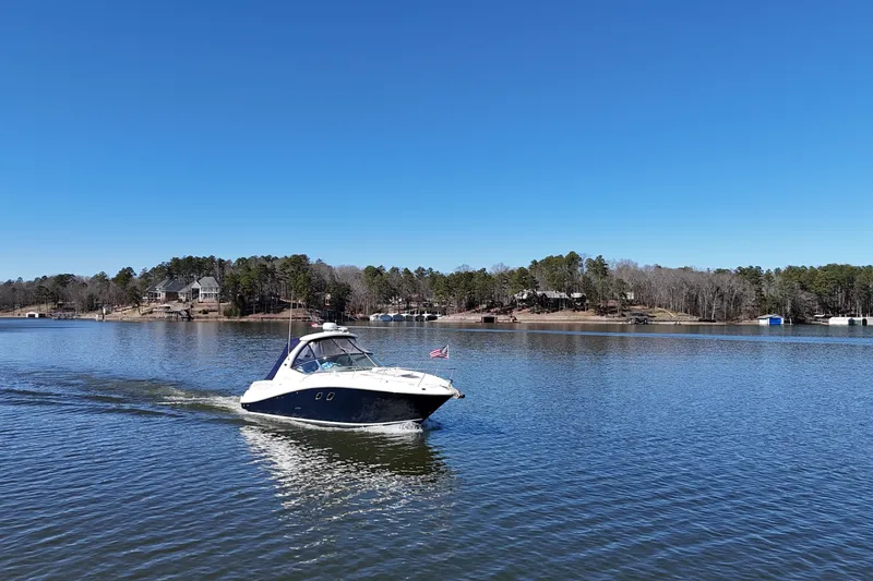 Slide: The Image of 2007 Sea Ray Sundancer 310 cruising on a serene lake under a clear blue sky. - 13