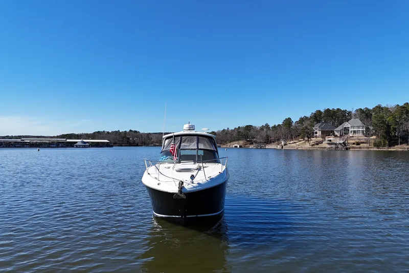 Slide: The Image of 2007 Sea Ray Sundancer 310 yacht on a serene lake with clear blue sky. - 8