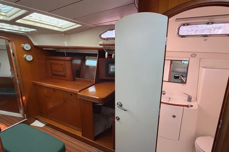 Slide: The Image of Interior of 2003 Beneteau Oceanis 393 yacht, featuring wood cabinetry and compact bathroom. - 14