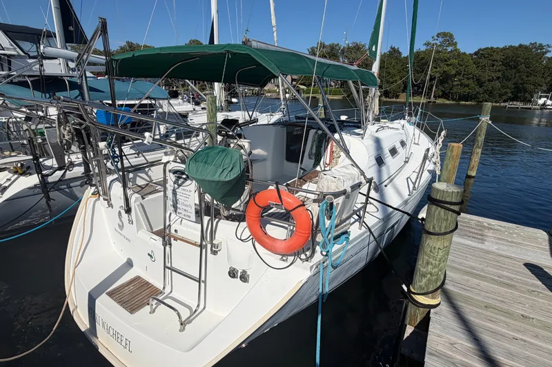 The Image of 2003 Beneteau Oceanis 393 sailboat docked, featuring green canopy and lifebuoy. - 1