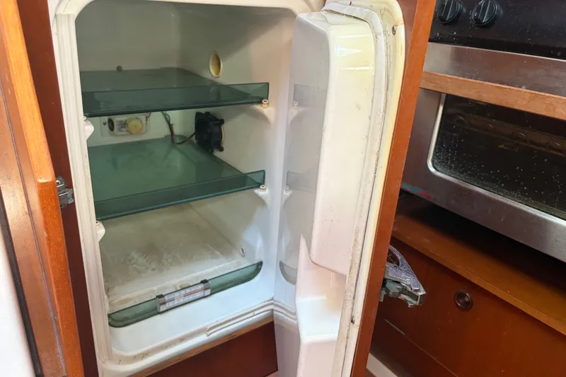 Slide: The Image of Open refrigerator inside 2003 Beneteau Oceanis 393 yacht, featuring glass shelves and adjacent oven. - 34