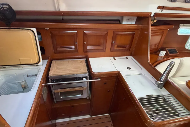 Slide: The Image of Interior view of 2003 Beneteau Oceanis 393 yacht kitchen with wooden cabinetry and appliances. - 5