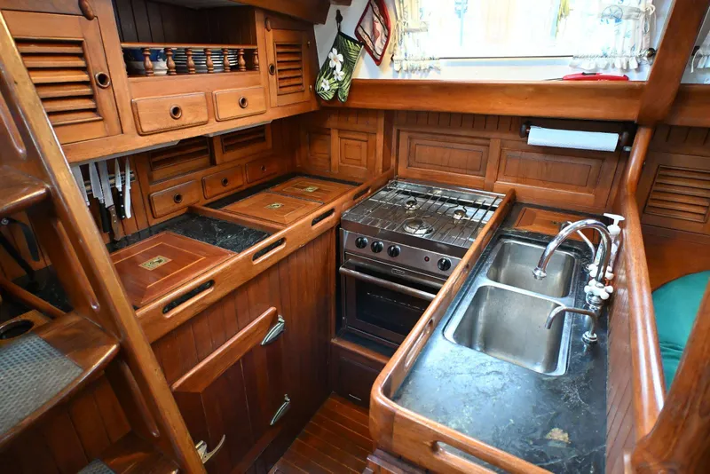 Slide: The Image of Vintage 1982 Passport Hoyt 45 yacht kitchen with wooden cabinetry and dual sink. - 49