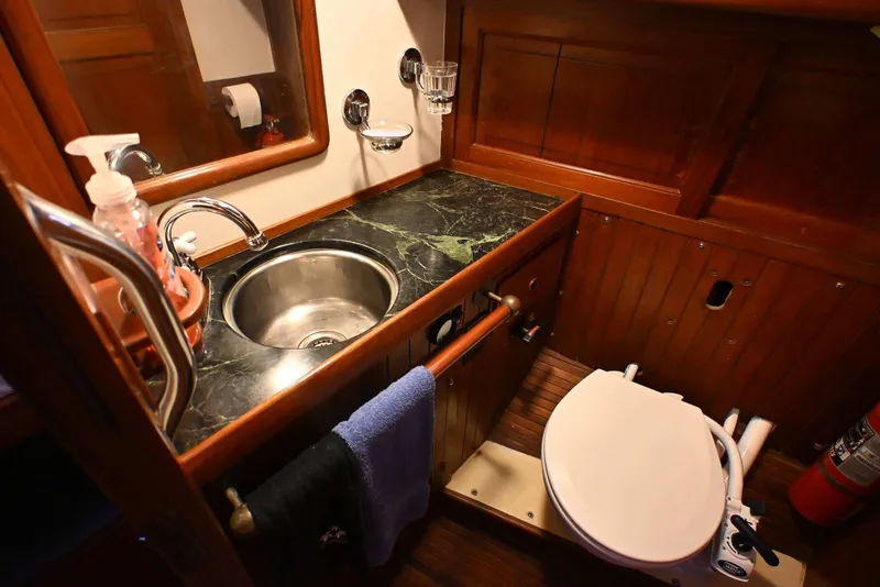 Slide: The Image of Vintage 1982 Passport Hoyt 45 yacht bathroom with wooden cabinetry and marble countertop. - 59