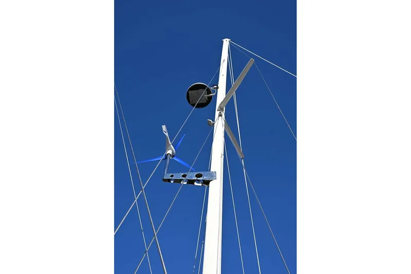 Slide: The Image of Sailboat mast with wind turbine and radar, Passport Hoyt 45, 1982 model, against clear blue sky. - 12