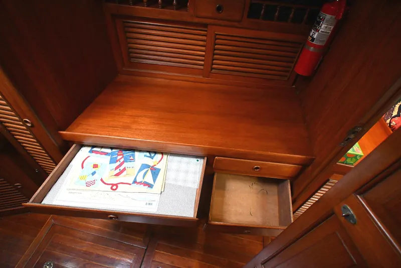 Slide: The Image of Wooden cabinet with open drawers, nautical-themed paper, and fire extinguisher, Passport Hoyt 45, 1982. - 76