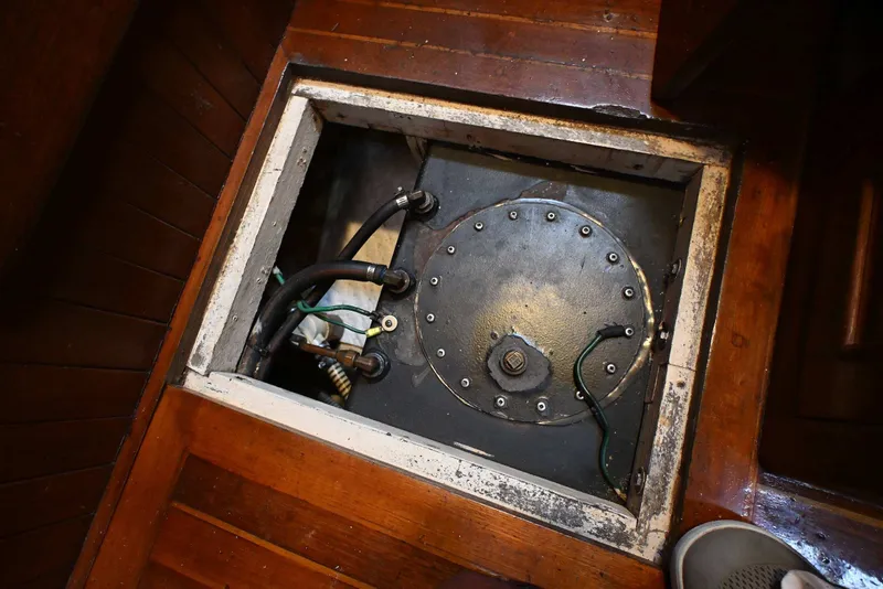 Slide: The Image of Boat engine compartment with visible hoses and metal cover, Passport Hoyt 45, 1982 model. - 89