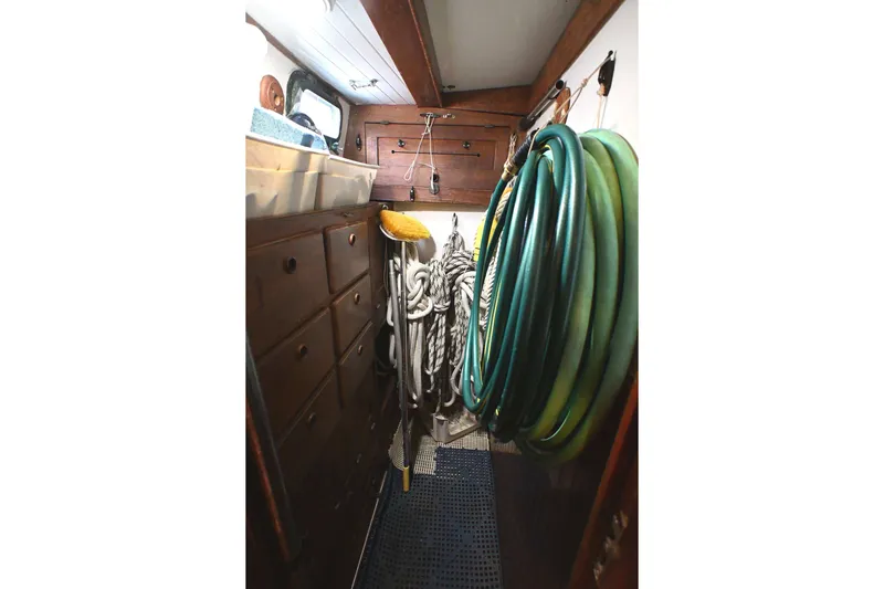 Slide: The Image of Nautical storage area with coiled hoses, ropes, and wooden cabinets on a 1982 Passport Hoyt 45. - 88