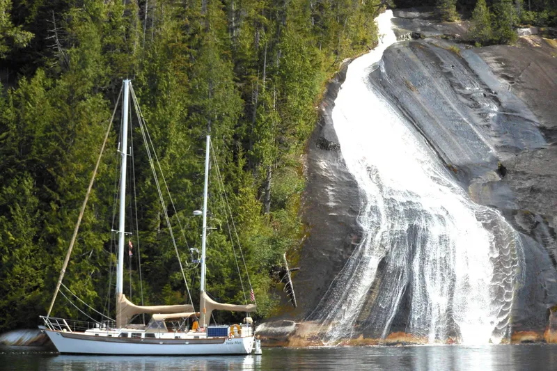 Slide: The Image of Sailboat near a waterfall with lush forest backdrop, Passport Hoyt 45, 1982 model. - 3