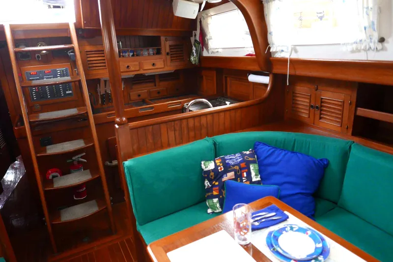 Slide: The Image of Cozy 1982 Passport Hoyt 45 yacht interior with green seating and wooden cabinetry. - 50