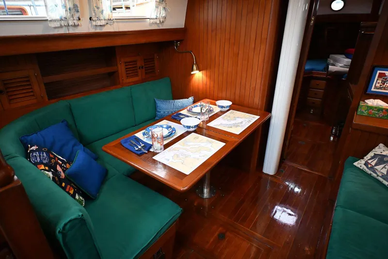 Slide: The Image of Cozy 1982 Passport Hoyt 45 yacht interior with green seating and dining setup. - 51