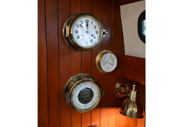 Slide: The Image of Vintage nautical instruments on wooden panel, featuring clock, barometer, and thermometer, Passport Hoyt 45, 1982. - 80