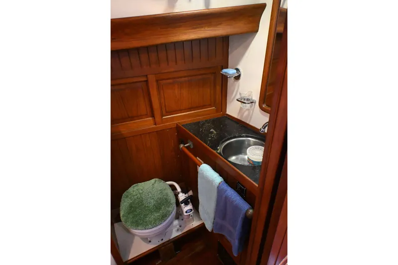 Slide: The Image of Compact wooden boat bathroom with sink, toilet, and towels, Passport Hoyt 45, 1982 model. - 54