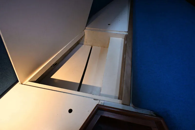 Slide: The Image of Interior storage compartment of 1982 Passport Hoyt 45 sailboat, featuring wooden panels and blue carpet. - 74