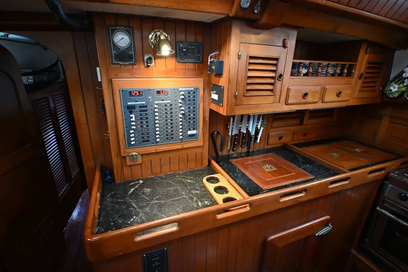 Slide: The Image of Wooden yacht galley with control panel, knives, and storage, Passport / Hoyt 45, 1982. - 68