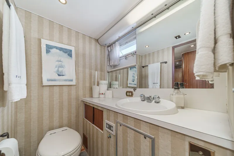 Slide: The Image of 1971 Hatteras 53 Motor Yacht bathroom with striped wallpaper and nautical decor. - 23