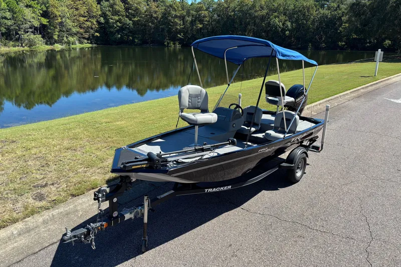 The Image of 2018 Tracker Pro 160 boat with canopy by a serene lake. - 1