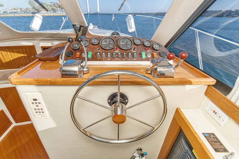 Slide: The Image of 1998 Riviera 34 Convertible yacht helm with steering wheel and control panel, overlooking the ocean. - 33
