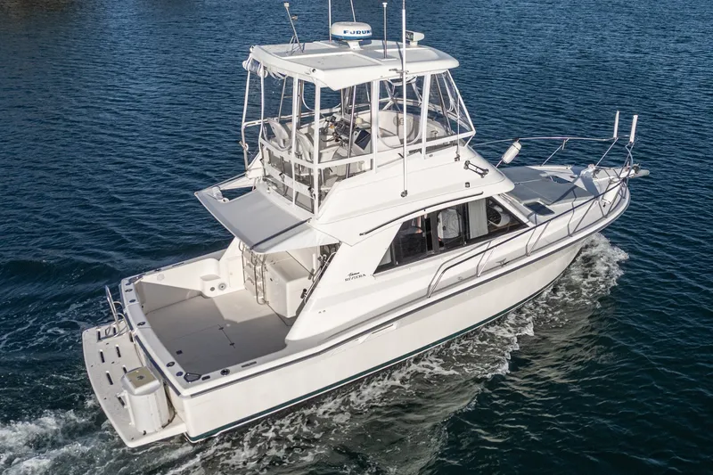 Slide: The Image of 1998 Riviera 34 Convertible yacht cruising on open water, showcasing sleek design and spacious deck. - 22