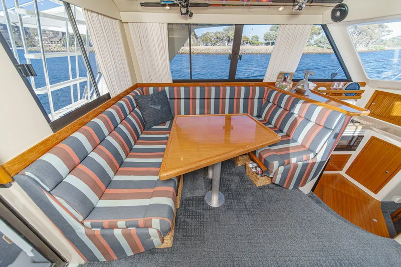 Slide: The Image of Interior of 1998 Riviera 34 Convertible yacht with striped seating and wooden table. - 28