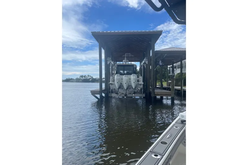 Slide: The Image of 2024 Wellcraft 38 Explorer docked under a covered boat lift on a sunny day. - 3