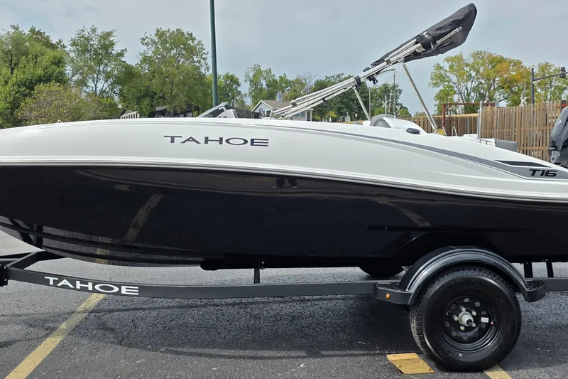 Slide: The Image of 2027 Tahoe T16 boat on trailer, parked outdoors with trees in background. - 1