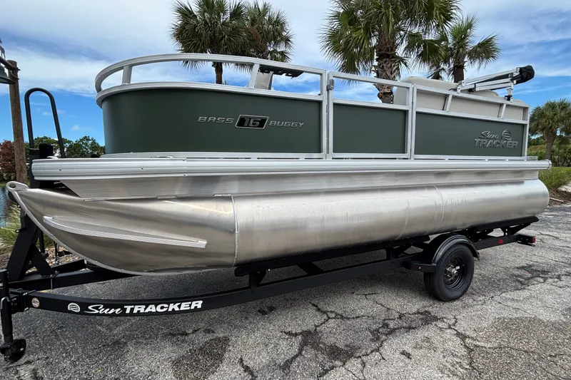 The Image of 2027 Sun Tracker Bass Buggy 16 XL Select pontoon boat on trailer, parked near palm trees. - 0