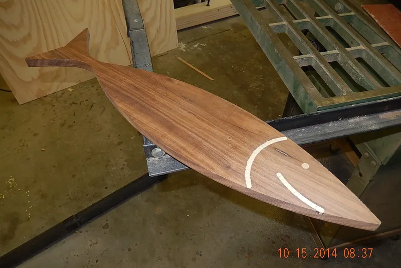 Slide: The Image of Wooden fish-shaped board on a workshop table, dated October 15, 2014. - 30
