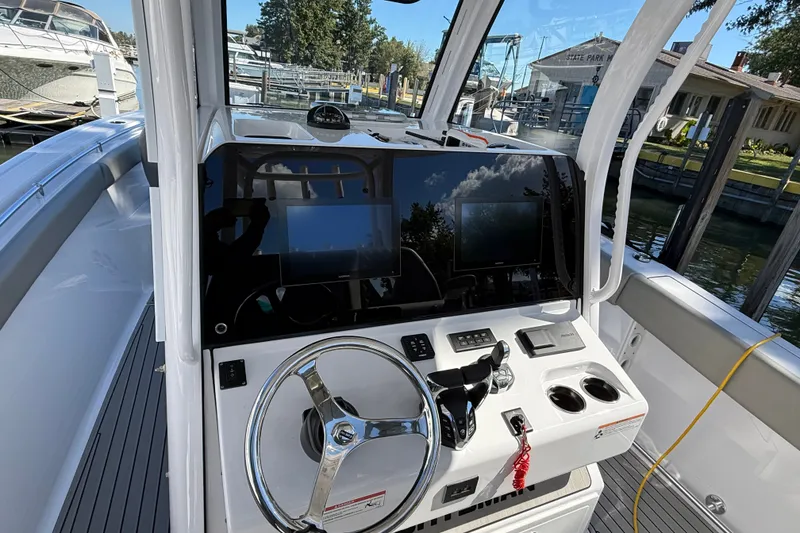 Slide: The Image of 2024 Sportsman Open 302 Center Console boat dashboard with steering wheel and controls. - 18