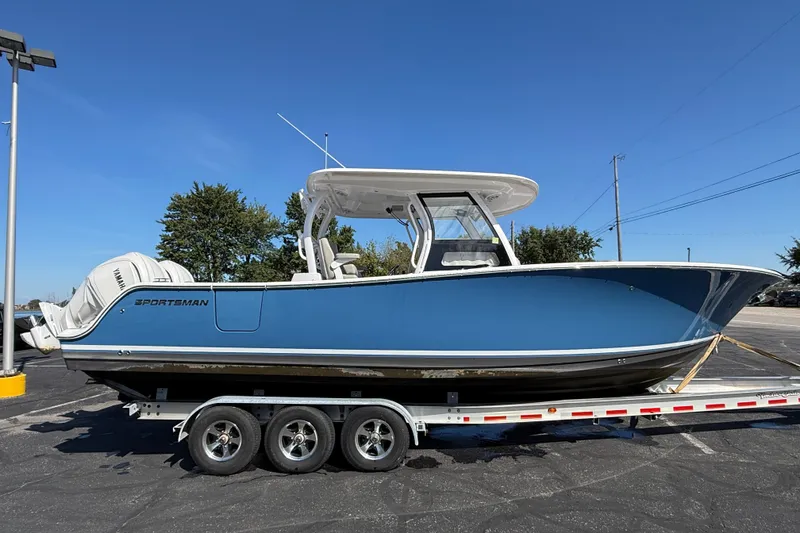 Slide: The Image of 2024 Sportsman Open 302 Center Console boat on trailer, blue hull, clear sky background. - 21
