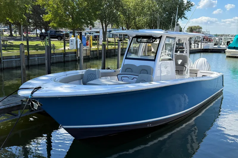 The Image of 2024 Sportsman Open 302 Center Console boat docked in a marina, surrounded by trees. - 0