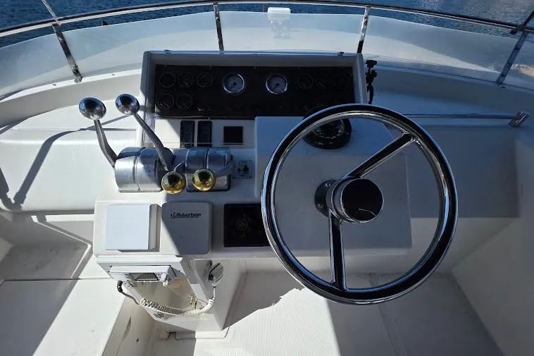 Slide: The Image of 1993 McKinna 48 Pilothouse helm with steering wheel and control levers. - 79