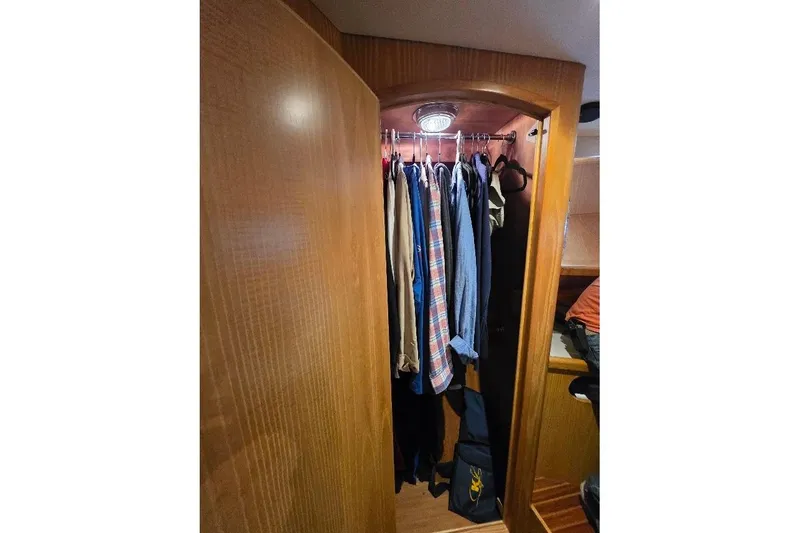 Slide: The Image of Clothing closet inside 1993 McKinna 48 Pilothouse yacht, featuring wooden interior and hanging garments. - 54