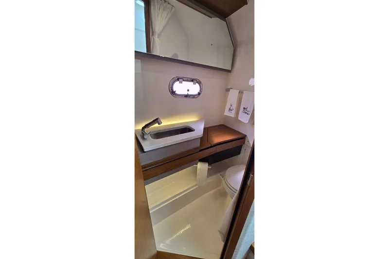Slide: The Image of 2022 Tiara Yachts 34 LS bathroom interior with modern sink, mirror, and porthole window. - 34