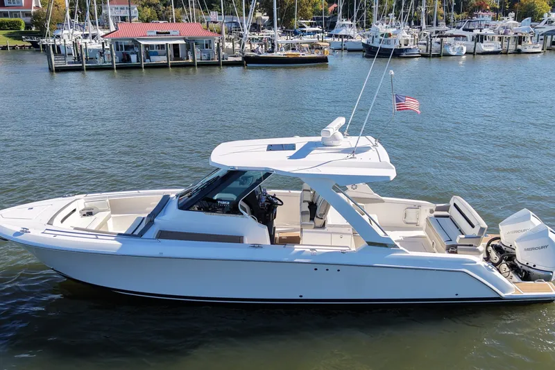 The Image of 2022 Tiara Yachts 34 LS boat docked in a marina with American flag. - 1