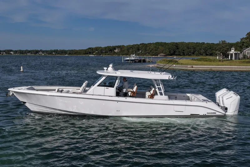 Slide: The Image of 2026 Everglades 455 Center Console boat cruising on a scenic waterway. - 16
