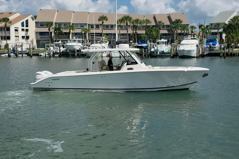 Slide: The Image of 2019 Pursuit S 328 Sport boat cruising in a marina with waterfront homes. - 17