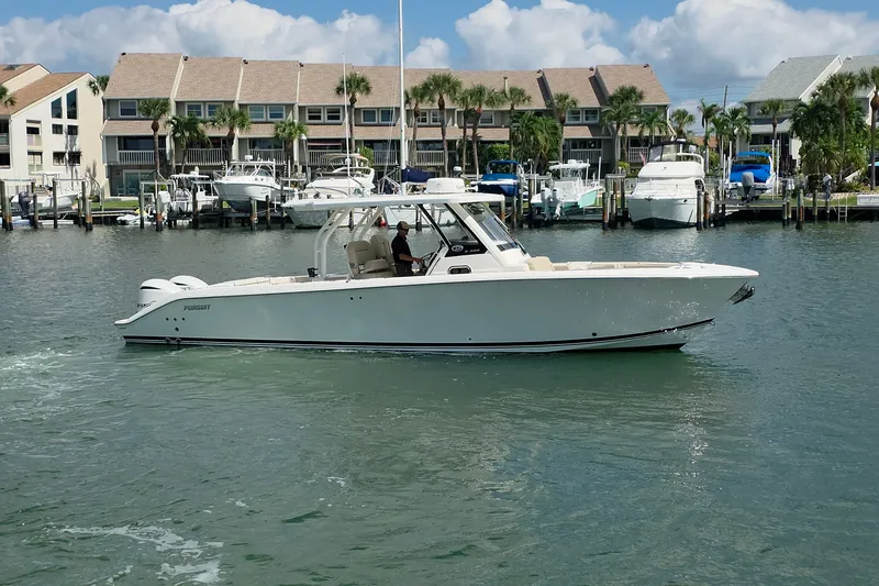 Slide: The Image of 2019 Pursuit S 328 Sport boat cruising in a marina with waterfront homes. - 18