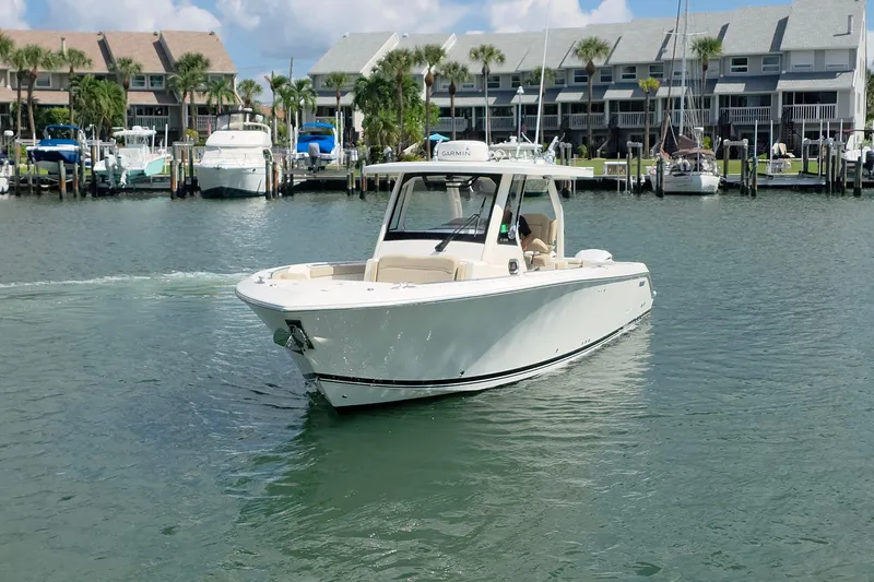 Slide: The Image of 2019 Pursuit S 328 Sport boat cruising in a marina with docked boats. - 22
