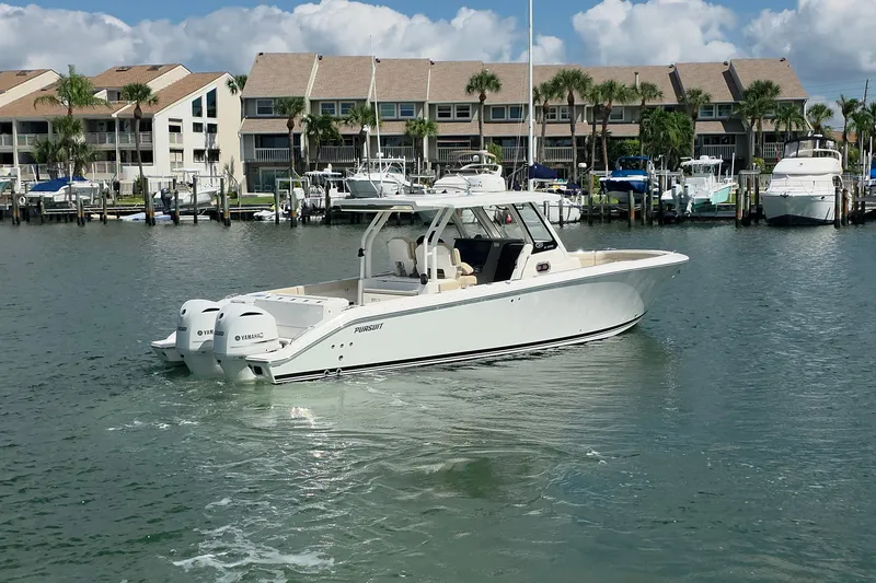 Slide: The Image of 2019 Pursuit S 328 Sport boat docked in marina with waterfront buildings. - 14