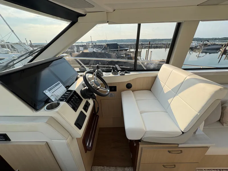 Slide: The Image of Interior view of a 2024 Regal 38 Grande Coupe helm station with white seating and large display. - 17