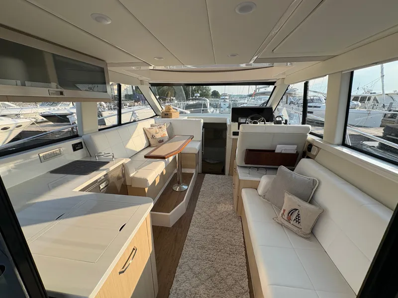 Slide: The Image of Interior of a modern yacht with sleek white seating, wooden table, and large windows. - 5