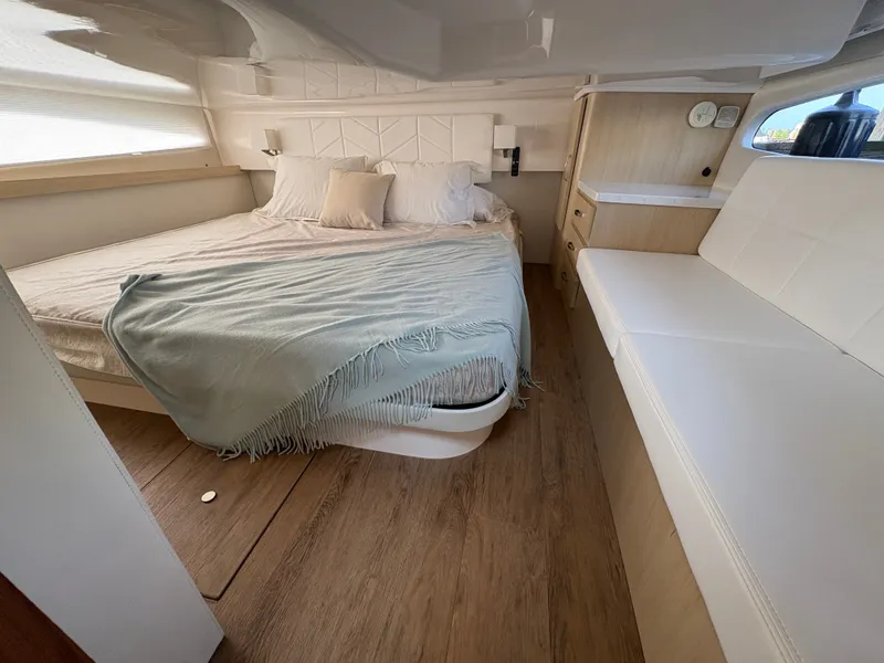 Slide: The Image of The cabin of the 2024 Regal 38 Grande Coupe features a cozy bed, wood flooring, and seating area. - 49