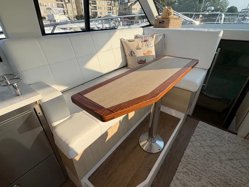 Slide: The Image of Interior of a 2024 Regal 38 Grande Coupe with white seating and a wooden table. - 12