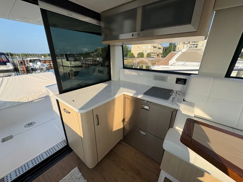 Slide: The Image of The 2024 Regal 38 Grande Coupe's galley features modern cabinetry and stainless steel appliances. - 7