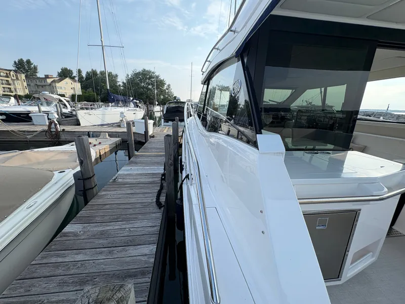 Slide: The Image of The 2024 Regal 38 Grande Coupe is docked at a wooden pier in a marina. - 38